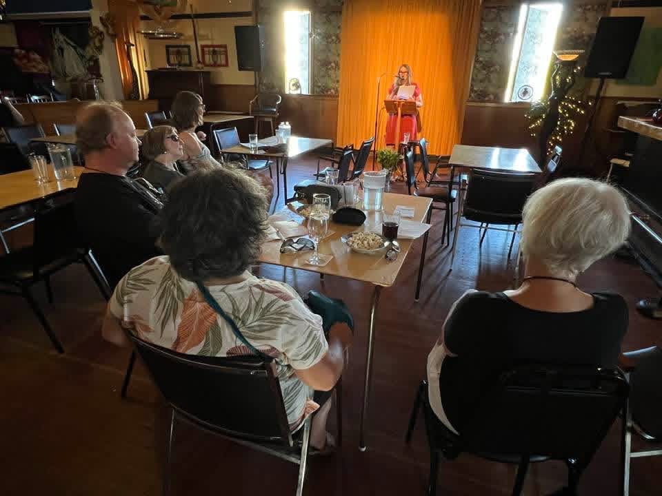 Margot standing reading at a podium at Char's Landing.